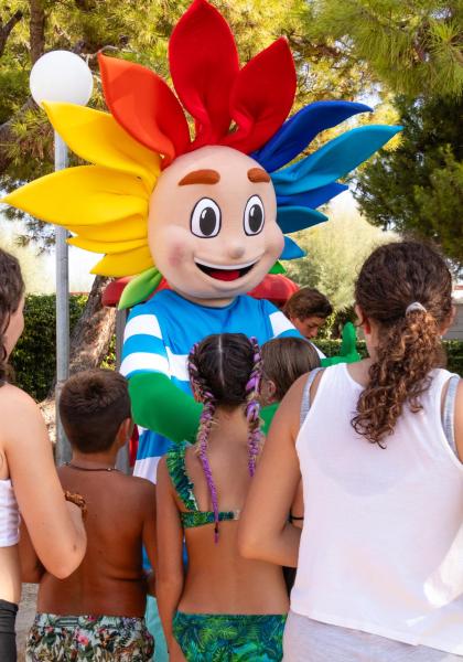 Personaggio colorato intrattiene bambini in un parco.