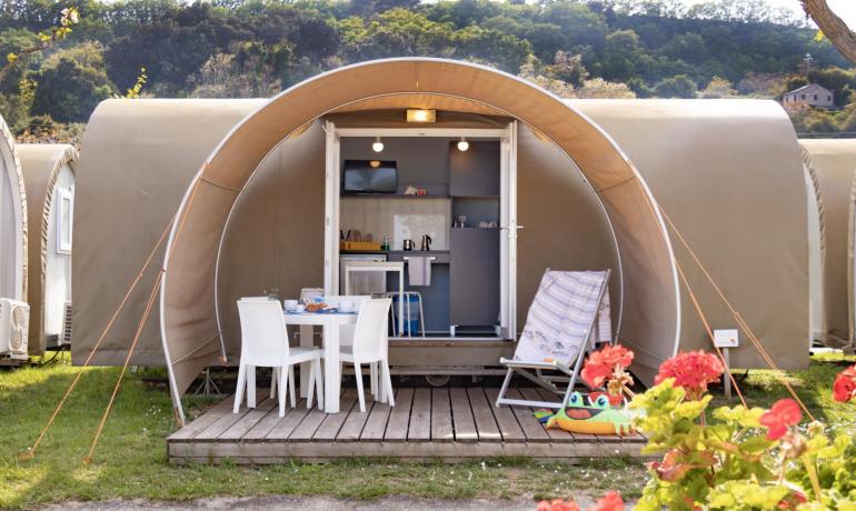 Moderne Zelt mit Veranda, Küche und Außenstühlen.