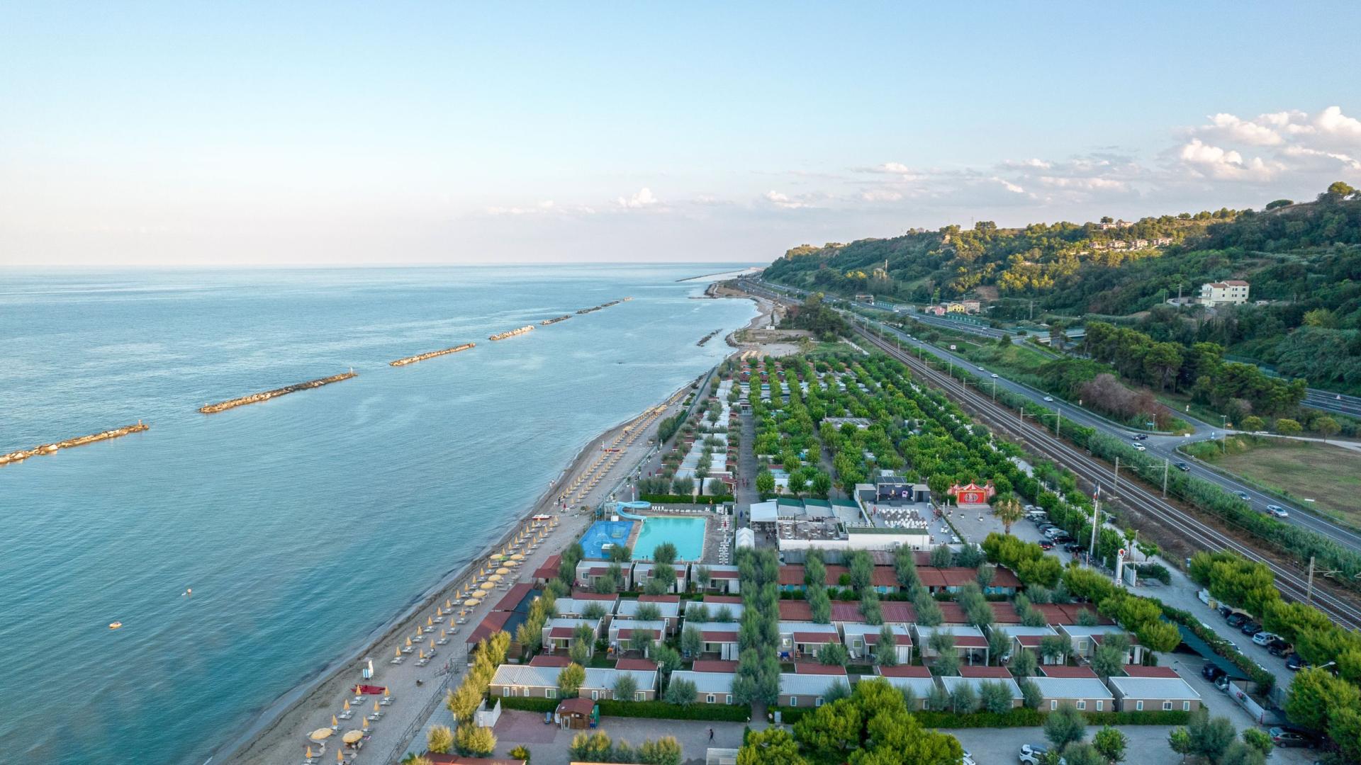 Vista aerea di una spiaggia serena con ombrelloni e mare calmo.