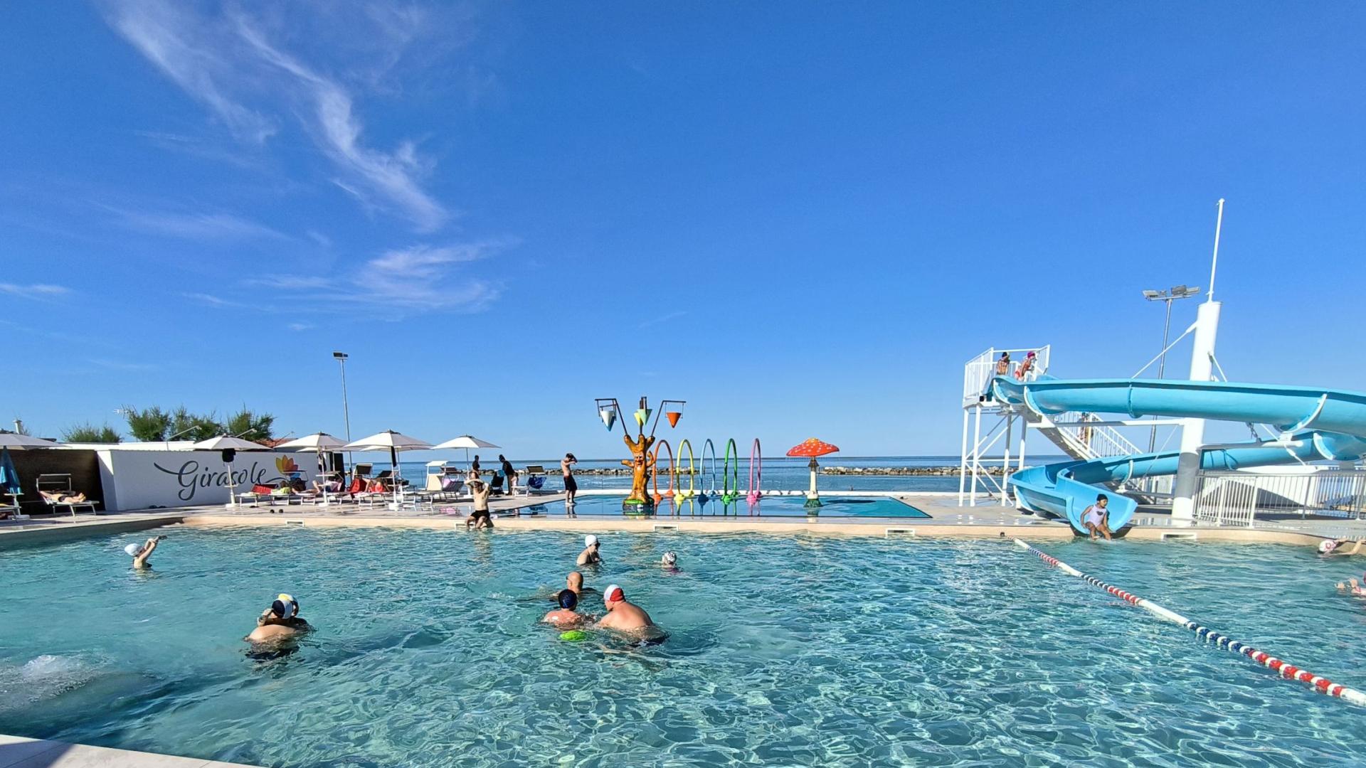 Piscina soleggiata, giochi d'acqua e scivolo, divertimento estivo e risate.