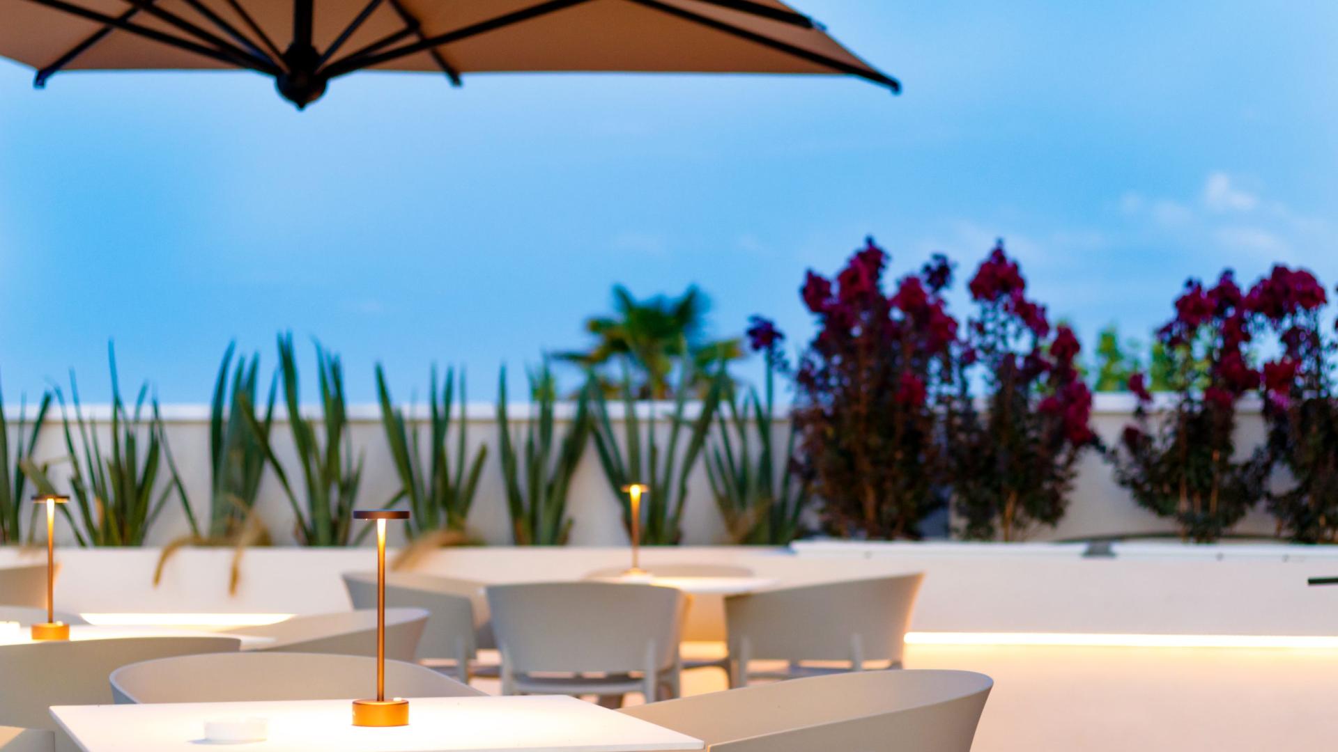 Terrazza elegante con tavoli illuminati, cielo sereno e luna piena.