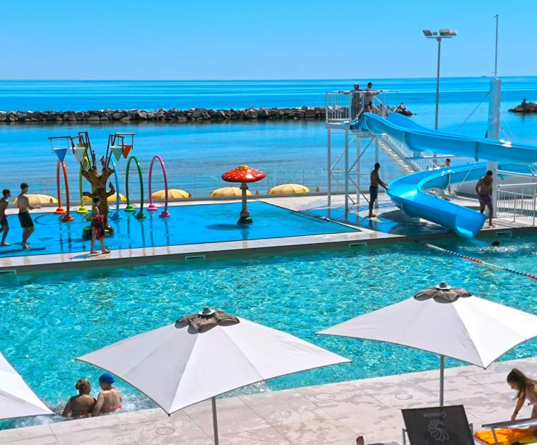 Piscina e scivolo sul mare, divertimento estivo sotto il sole.