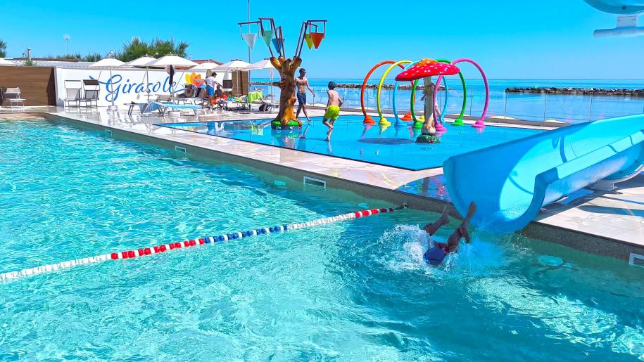 Piscina estiva con scivolo, giochi d'acqua e gioia sotto il sole.