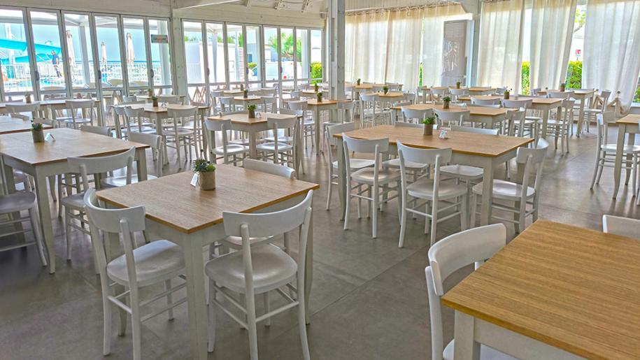 Ampia sala luminosa con tavoli in legno, atmosfera accogliente e serena.