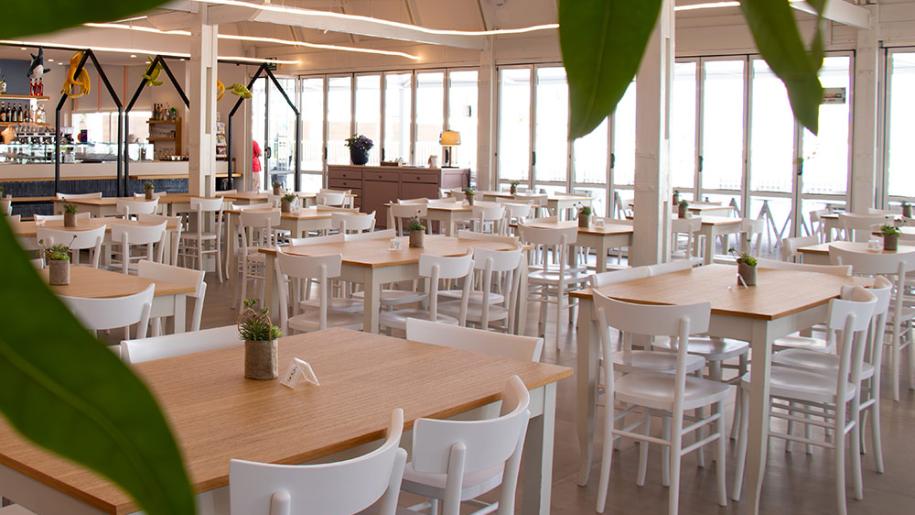 Ristorante luminoso con tavoli in legno, atmosfera accogliente e moderna.