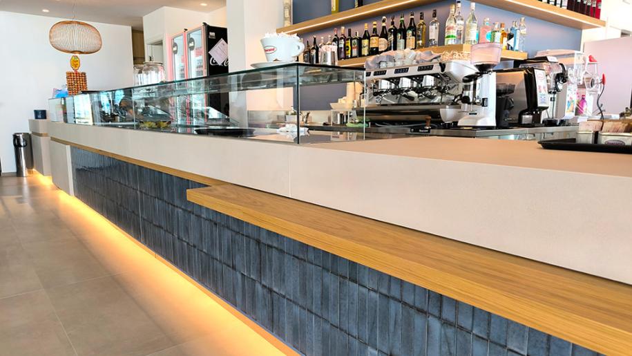 Bar moderno, linee pulite, luci calde, atmosfera accogliente e vivace.